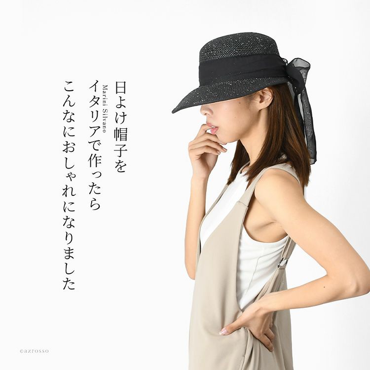 イタリア製の黒いつば広ペーパーハットをかぶった女性モデル。太リボンとシルバーラメが大人可愛い夏のUVカット帽子。