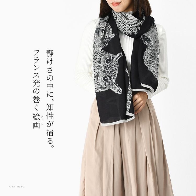 黒地にフクロウ、オウムと一匹の猫が描かれた上品な大判ウールストール。INOUI EDITIONS イヌイエディションズの軽い暖かい秋冬向けレディースストールを白ニットとベージュスカートに合わせたレディースコーデ